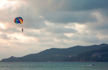 Towing boat pulls out a parachute with a tourist and an instructor, cloudy evening sky