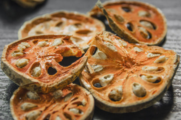 Dried herbs and dried bael fruit, Close-up of bael dry on the wooden floor, Many of slices of bael fruit for make bael juice on the dark table.