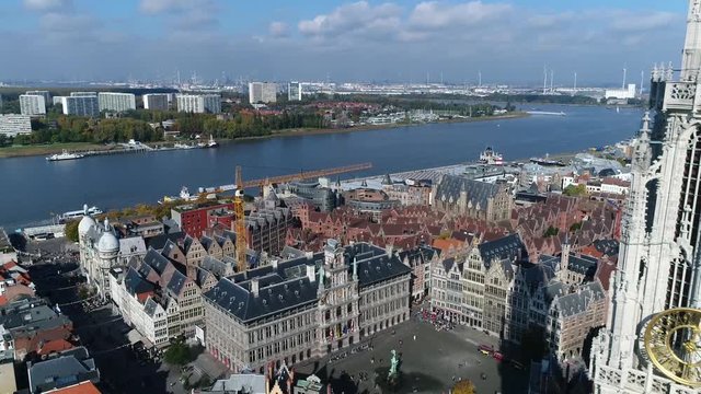 Urban aerial Antwerp backwards flight past The Cathedral of Our Lady tower in Dutch Onze-Lieve-Vrouwekathedraal is Roman Catholic cathedral Antwerp Belgium also showing Scheldt river 4k quality