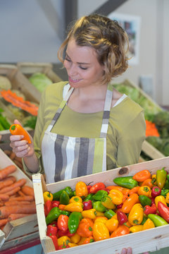 joyful smiling female worker choosing fruits in food shop