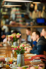 Table with flowers and people setting around