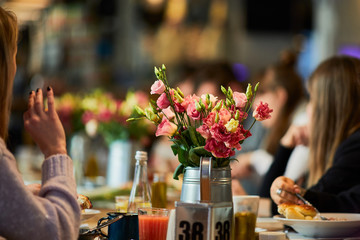 Table with flowers and people setting around