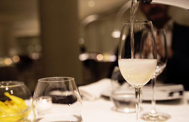 the waiter at the cafe pours champagne into the glass