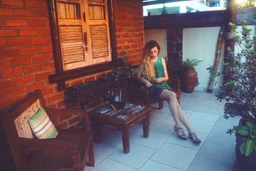 young woman sitting on armchair on terrace in summer day