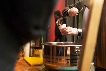 mulled wine and punch are poured into a glass from a large saucepan