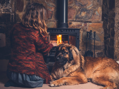 Woman with dog relaxing by fire