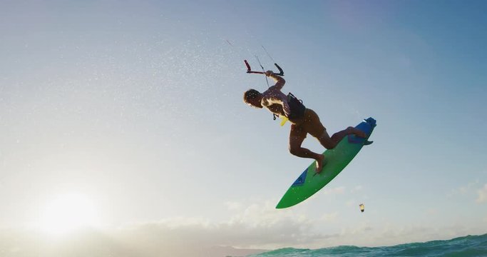 Kitesurfing at sunset in slow motion, kiteboarder gets big air