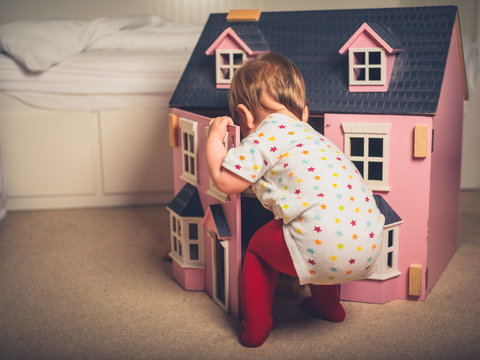 Toddler playing with doll house