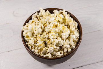 Bowl with popcorn on wooden table