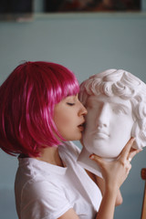beautiful girl in a pink wig under the square with a bang and a plaster head.