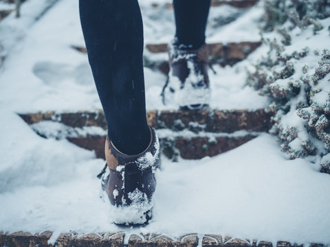 Feet of young woman walking up stairs in snow