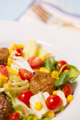 Colorful fresh vegetable salad with meatballs and corn seeds