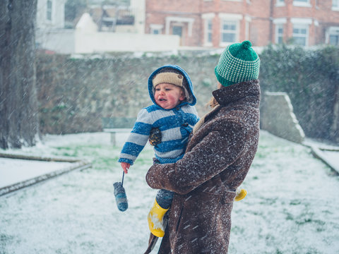 Young mother carrying toddler in the snow