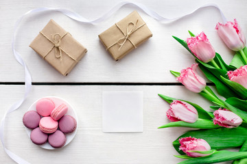 Tulips, gift boxes and macaroons wooden white background