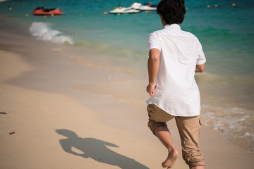 behind of a man is running on tropical beach in morning. traveling and relaxation concept background
