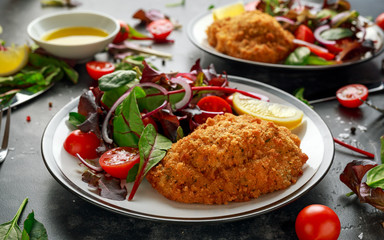 Breaded Chicken Kiev breast stuffed with butter, garlic and herbs served with vegetables in a plate.