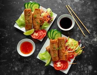 Chinese vegetable spring rolls garnished with fresh salad, lime wedges, sweet chilli sauce and soy...
