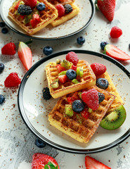 Fresh egg waffles dessert for breakfast with fruits strawberries, blueberries, blackberries, raspberries and kiwi