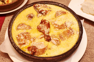 Roasted chicken with creamy sauce in cast iron frying pan on dark wooden background
