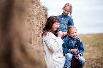 family - mother and two daughters are resting near the hay