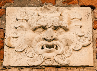 Frightening demon face old relief on wall in Venice