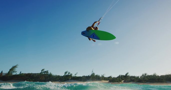 Kitesurfing at sunset in slow motion, kiteboarder gets big air