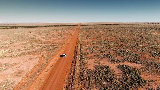 Drone shot vehicle traveling dusty road in Australian Outback. 