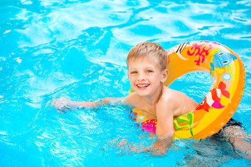 Fototapeta na wymiar Boy floating on an inflatable circle in the pool
