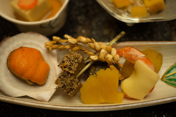 Assortment of seafood served which includes a clam, prawn, pickled vegetable served as an entree as part of a traditional Japanese dinner also known as Keiseki being served at a Ryokan