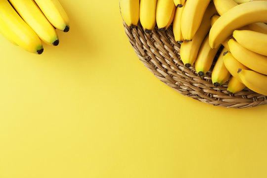 Wicker mat with yummy ripe bananas on color background