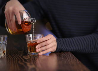 Woman pouring alcohol into drink at bar, closeup. Alcoholism problem
