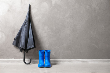 Black umbrella and gumboots on floor indoors