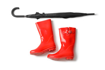 Black umbrella and gumboots on white background