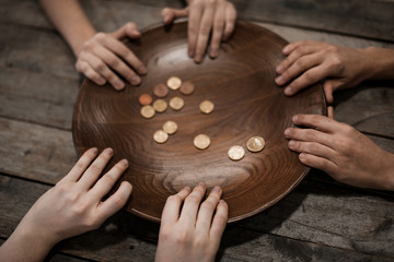 Poor people holding plate with coins on wooden background