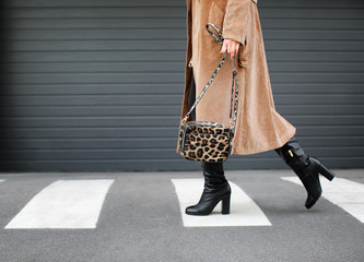 Stylish woman in black shoes walking across the street