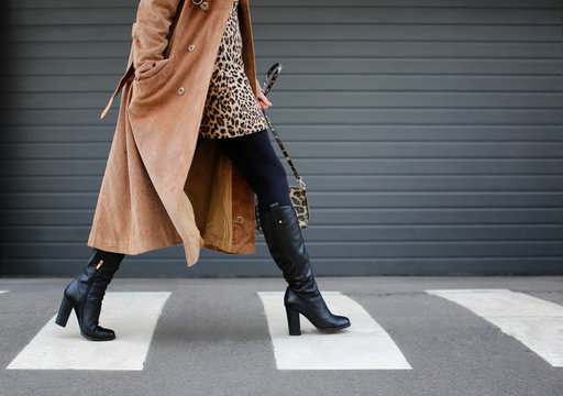 Stylish woman in black shoes walking across the street