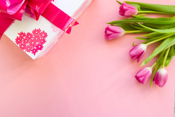 gift with pink ribbon and pink tulips on pink background