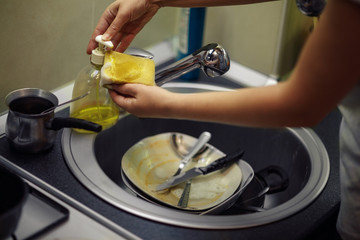 washing dishes. hands in foam washes the frying pan with a detergent and sponge in the kitchen.