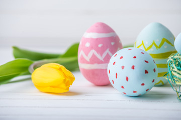 Colorful Easter eggs with yellow Tulip hand painted on a white wooden background. Festive spring card