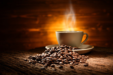 Naklejki  Cup of coffee with smoke and coffee beans on old wooden background