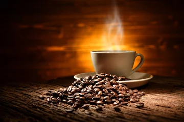 Foto op Plexiglas Cup of coffee with smoke and coffee beans on old wooden background © amenic181