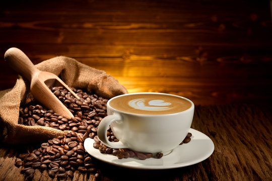 Cup of coffee latte and coffee beans on old wooden background
