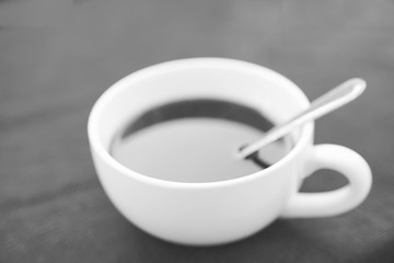 White cup of black coffee on black background in black and white
