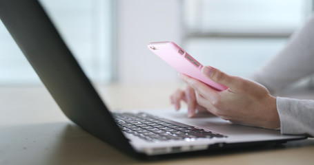 Woman working on laptop computer and use of cellphone