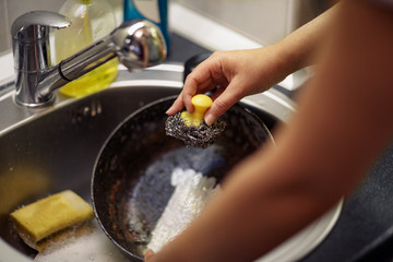 female hand with sponge washing dish in the kitchen.