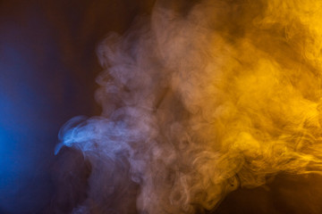 Blue and yellow smoke on a dark background. Texture and desktop picture