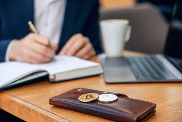 Businessman works in his workplace with notebook, laptop and makes a business plan. Cryptocurrency mining. Golden and silver bitcoin coin. Selective focus.