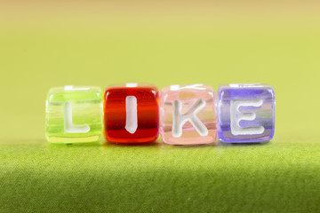 color cube figure with word LIKE on green book