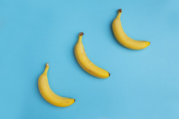 three bananas on a blue background diagonally