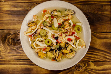 Seafood salad with shrimp, squid and mussels on wooden table